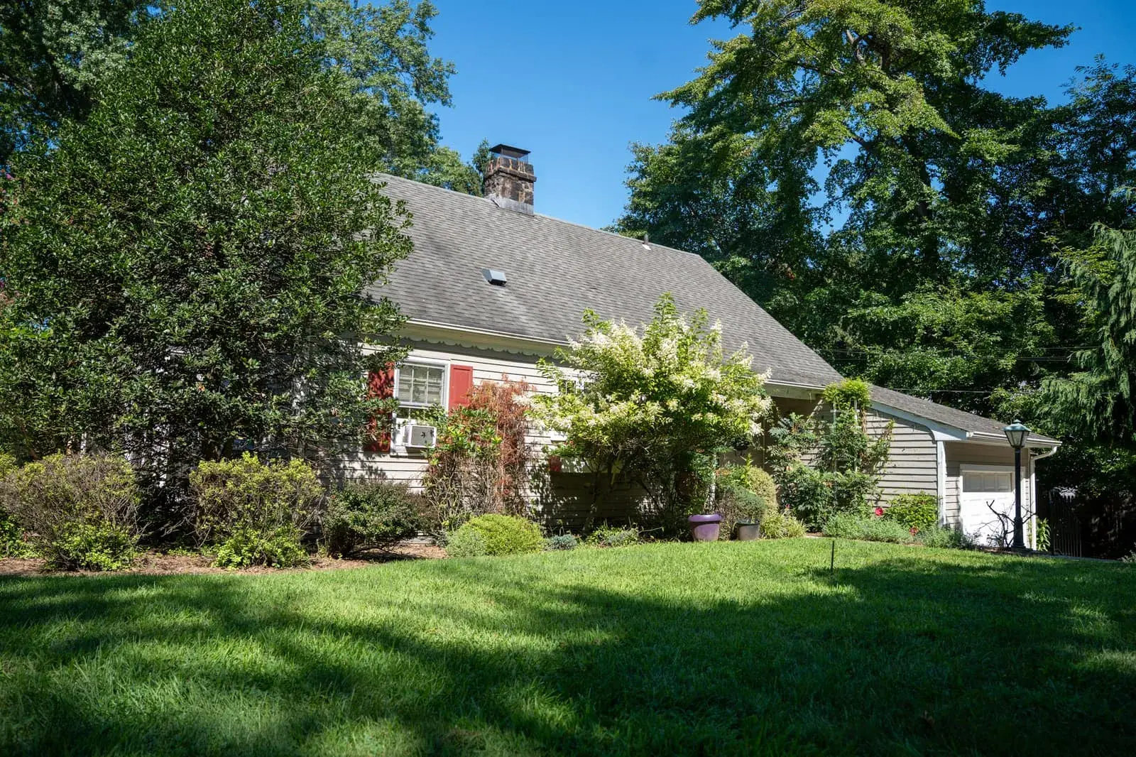 Front of Closter Residence II with red shutters and flowering shrubs, Closter, NJ