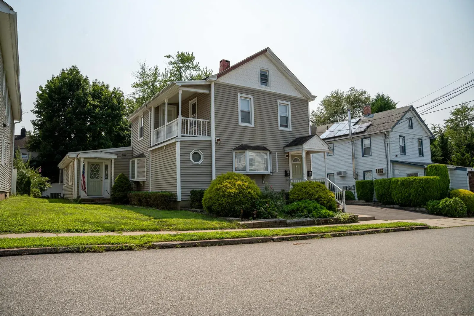 The Waldwick sober living house from the street: a grey two-story home with a front porch and upstairs balcony, Waldwick, NJ