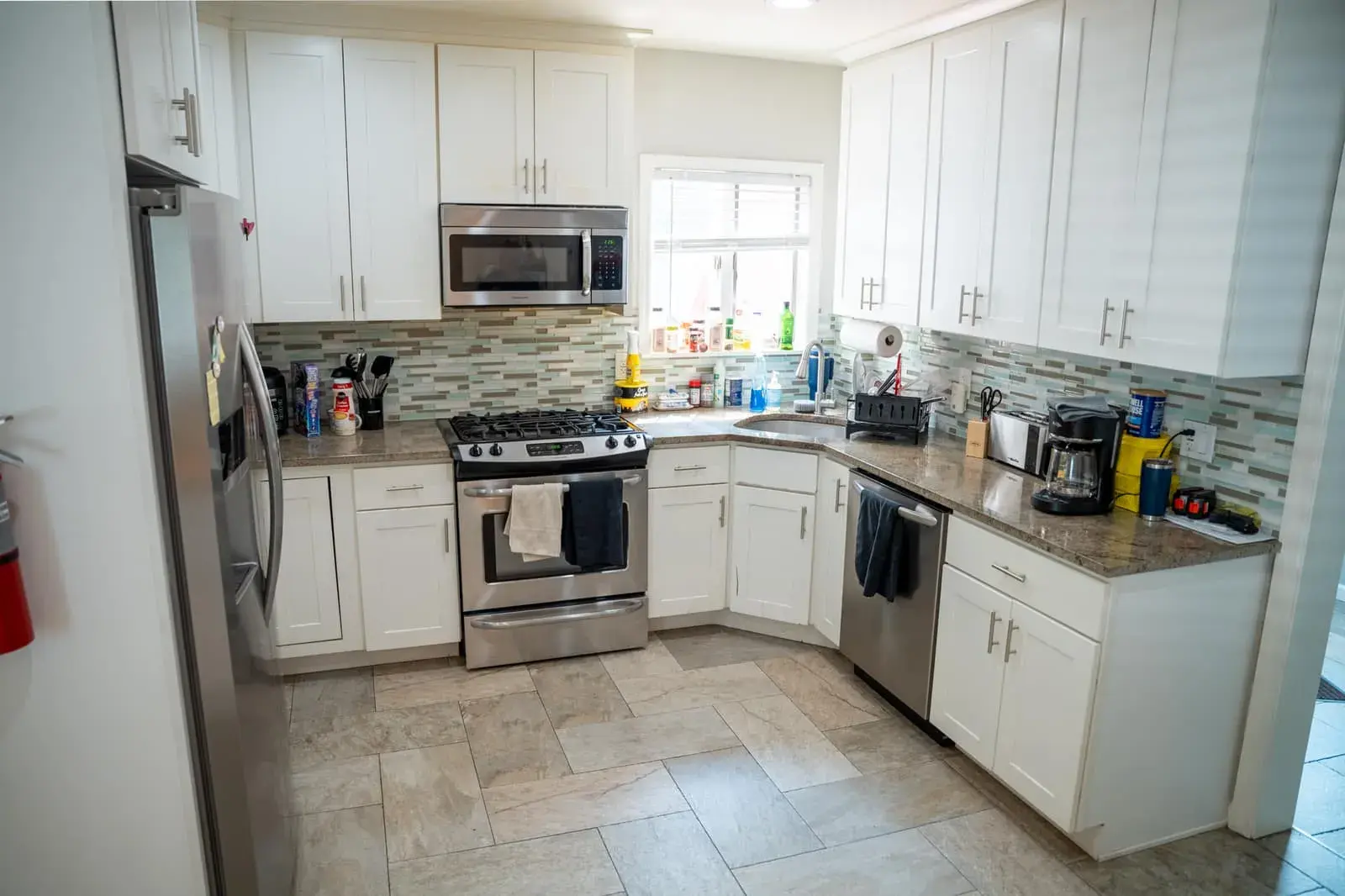 The kitchen at the Waldwick house: white cabinets, a gas range, stone counters and a tiled floor