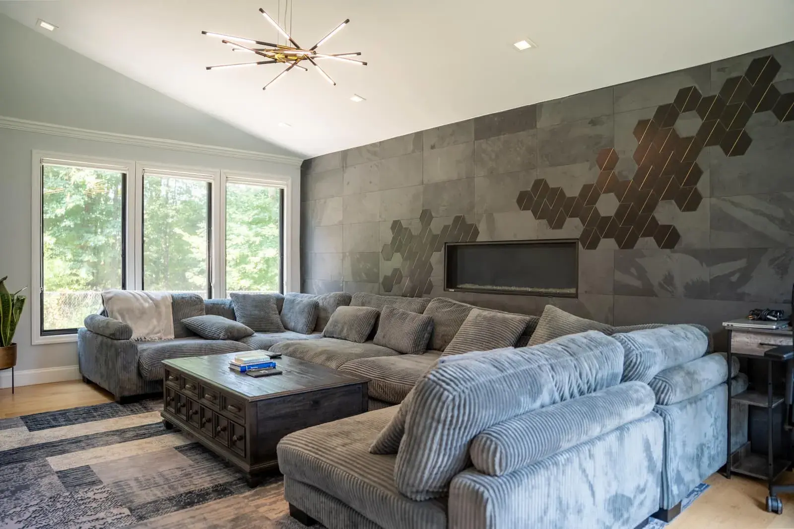 The living room in Closter Residence I: a large gray sectional sofa and a wooden coffee table under a vaulted ceiling