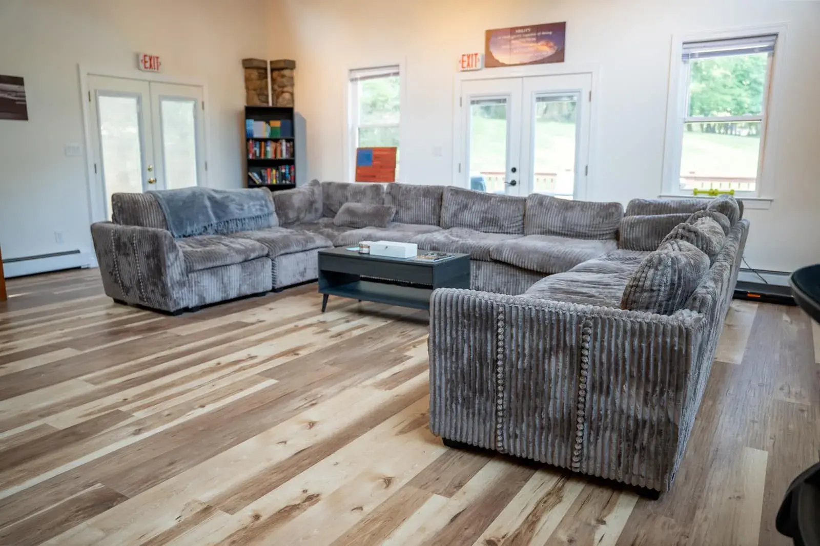 A living room in the Old Tappan house: a large grey sectional sofa, a bookshelf and French doors to the yard